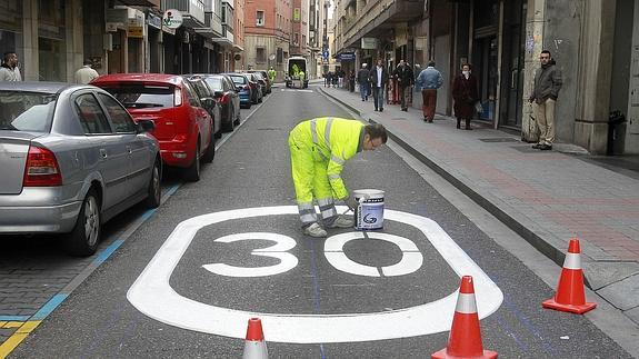 Un operario pinta una señal de 30 km/h.