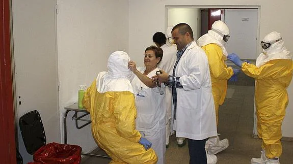 Miembros del personal médico se colocan los trajes de protección para atender a Manuel Garcia Viejo. 