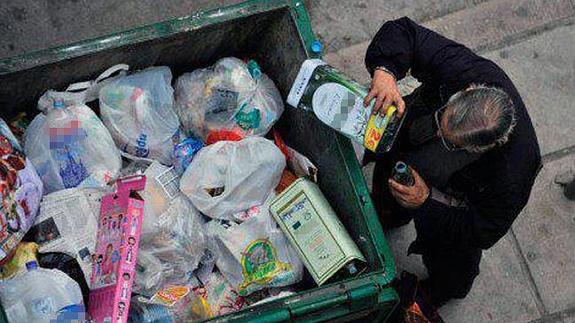 Un hombre buscando comida en la basura 