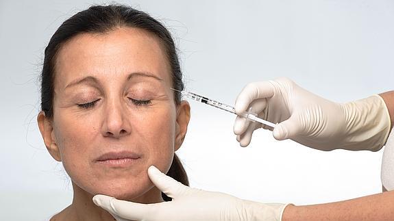 Un cirujano inyecta botox en la piel de una mujer. 