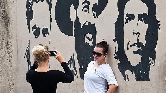 Una mujer se fotografía ante un mural en La Habana.