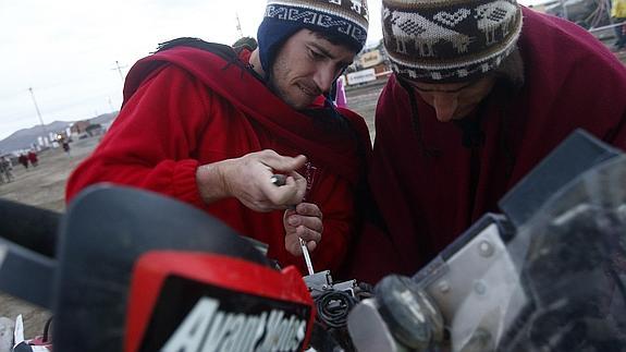 Barreda (I) desmonta el manillar de la moto de su compañero de equipo, Demian Guiral. 