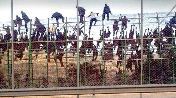 Decenas de inmigrantes escalando la valla de Melilla, en un punto donde no tiene concertina.
