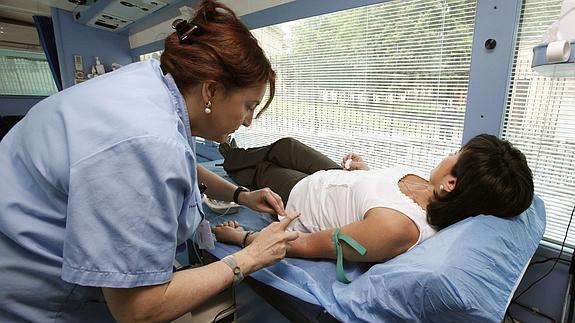 Una mujer dona sangre una unidad móvil.