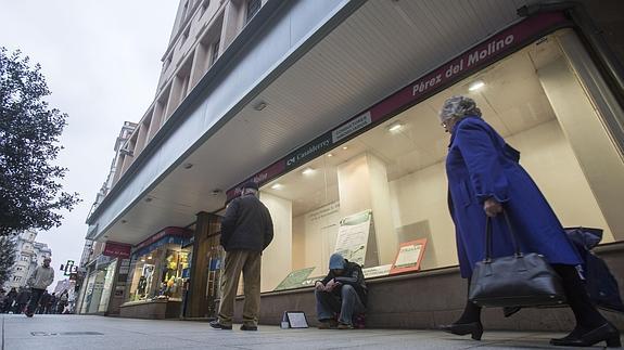 Mendigo pide a la puerta de un centro comercial.