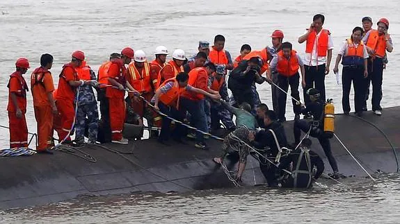 Miembros de los servicios de rescate ayudan a un superviviente tras el naufragio. 