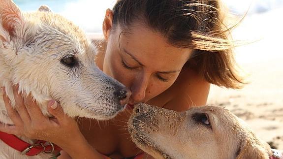 Una chica posa junto a sus dos perras en una playa de Cádiz.