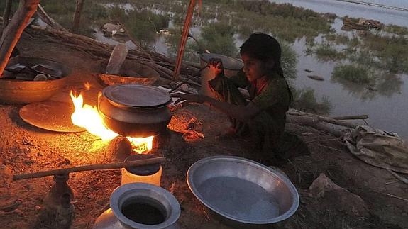 Una niña paquistaní cocina en un refugio temporal de la zona inundada.