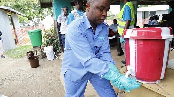 Un hombre se lava las manos con agua y cloro en Liberia.