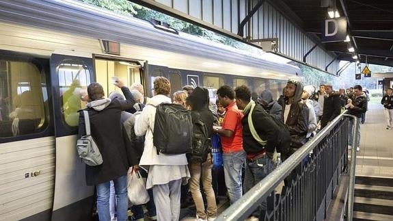 Refugiados y viajeros toman un tren en la estación de tren de Flensburg, en Alemania.