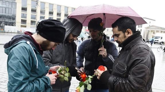 Refugiados sirios encienden velas en Berlín por las víctimas de los atentados. 