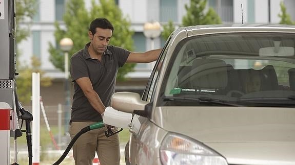 Un hombre repostando en una gasolinera. 