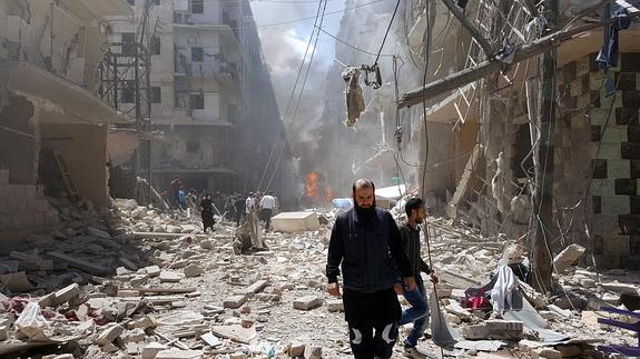 Varias personas caminan entre los escombros tras los bombardeos en Alepo, Siria.