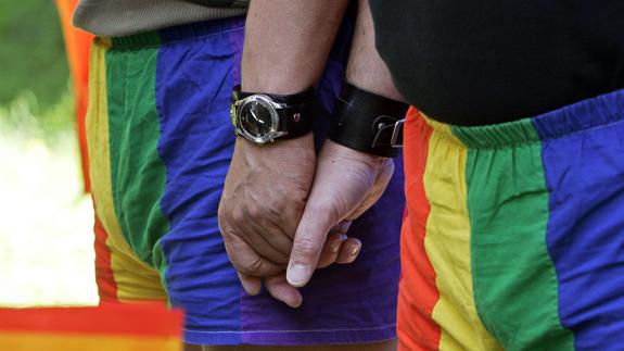 Una pareja se da la mano mientras participa en una marcha con motivo del día internacional del orgullo gay.