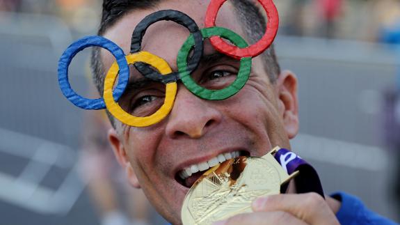 Un hombre simula morder una medalla de oro.