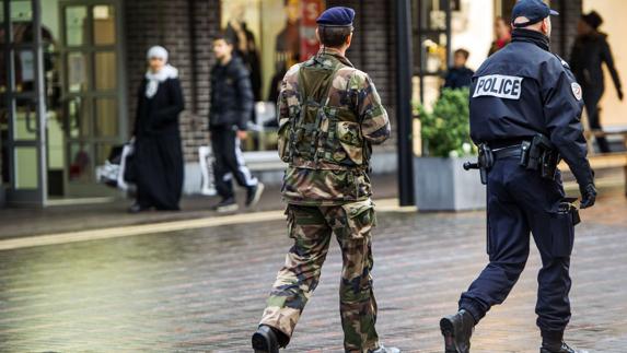 Un soldado y un policía francés patrullan conjuntamente por una calle de Paris.