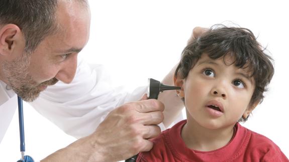 Un otorrinolaringólogo realiza una revisión auditiva a un niño.