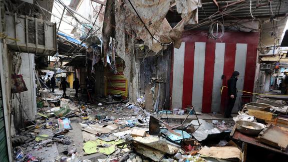 Varios iraquíes inspeccionan el lugar del atentado en el mercado Sinak.