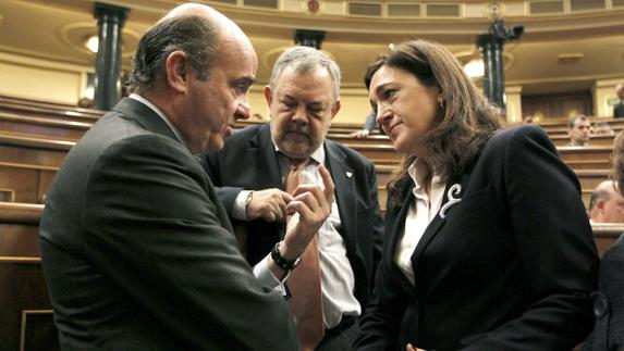 Luis de Guindos (i), conversa con Soraya Rodríguez (d), en presencia Pedro María Azpiazu. 