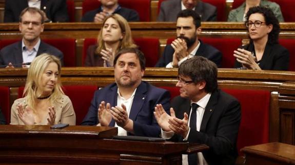 Carles Puigdemont y Oriol Junqueras aplauden una votación en el Parlamento de Cataluña.