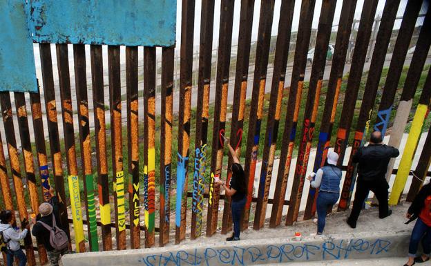 Ciudadanos mexicanos pintan el muro fronterizo entre México y Estados Unidos. 