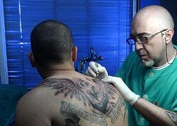 Javier Herrera realiza un tatuaje en la espalda a un joven./ANDREA CENICEROS
