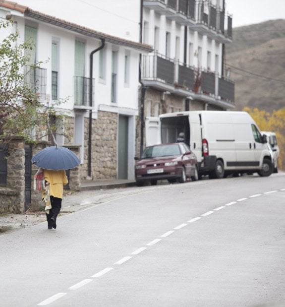 Una persona camina por la travesía de la LR-250 en San Román de Cameros. 