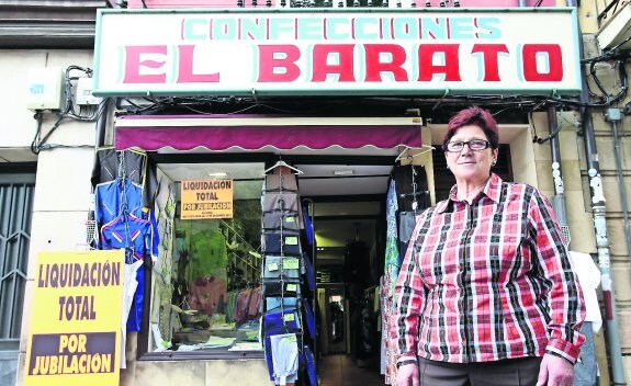 Felicidad posa junto al reconocible cartel de El Barato, en la plaza del Mercado, donde anuncia el cierre para el 31 de diciembre. 