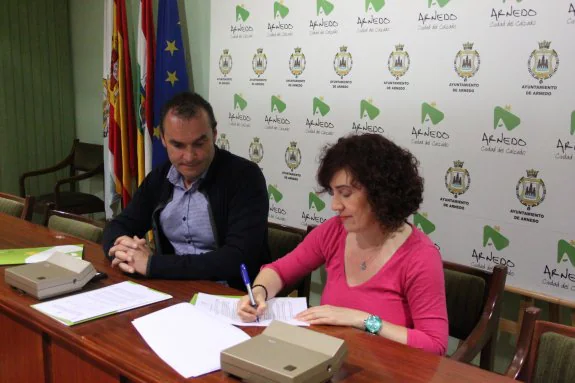 El concejal Toño Eguizábal observa cómo Ana Osés firma el convenio de colaboración. 