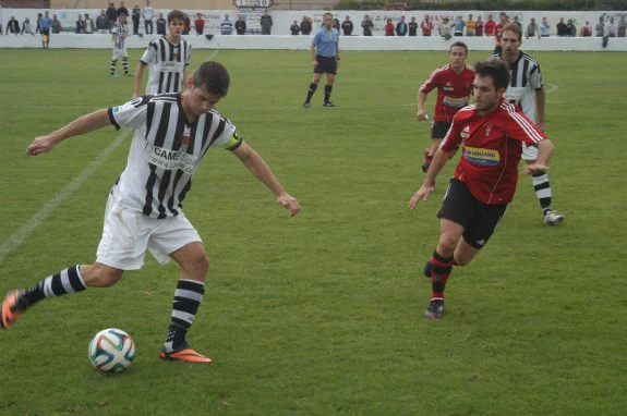 El blanquinegro López, con el balón, ante el rojillo Octavio.