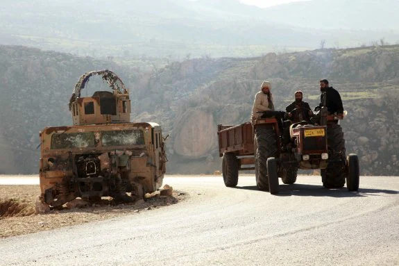 Tres yazadíes pasan junto a un vehículo quemado del Estado Islámico en Sinyar. 