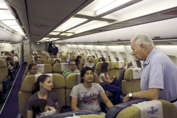 José Manuel García Margallo conversa con varios españoles en el avión que los repatrió ayer desde Nueva Delhi. :: Zipi / efe