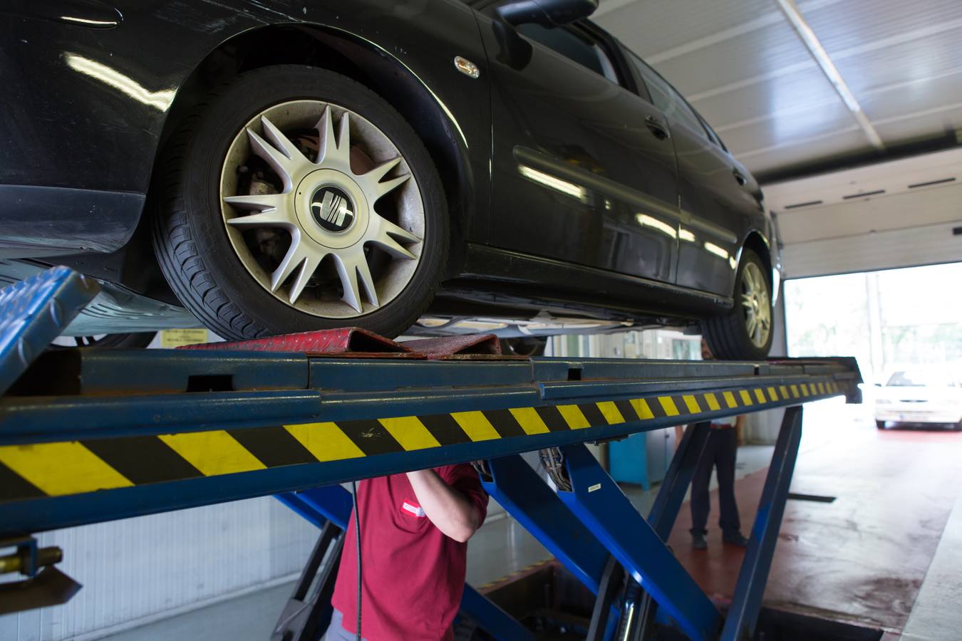 Un operario inspecciona los bajos de un automóvil. 