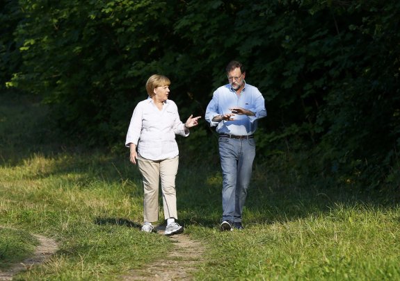 Merkel y Rajoy caminan
ayer en las cercanías del castillo de Meseberg, residencia de huéspedes del Gobierno alemán.  