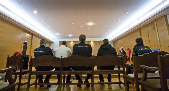 Los acusados, separados por un agente de la Policía, sentados en el banquillo de la Audiencia Provincial durante el juicio. :: justo rodríguez
