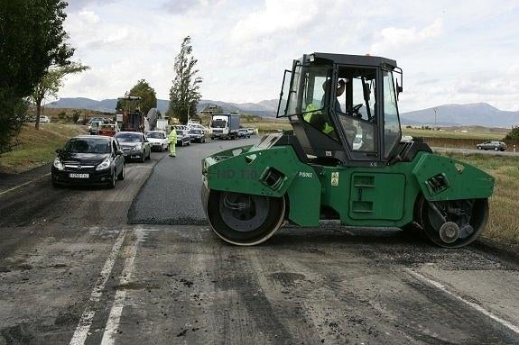 Dos operarios reasfaltan un tramo de una carretera en mal estado. :: A. Gómez