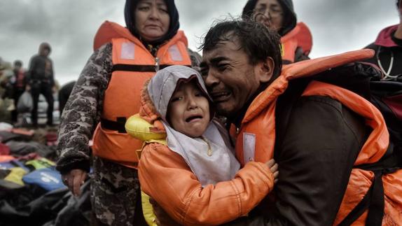 Un padre trata de consolar a su hija en la isla de Lesbos.  