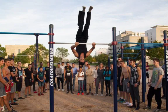 Joven haciendo calistenia en un gimnasio al aire libre usando barras  paralelas hace flexiones en la barra