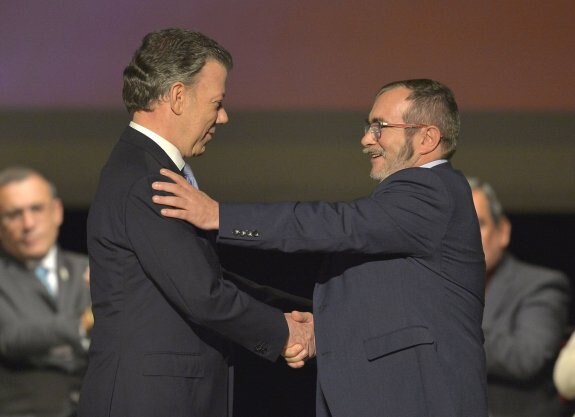 Santos y 'Timochenko' se estrechan las manos durante la ceremonia. :: LUIS ROBAYO / afp