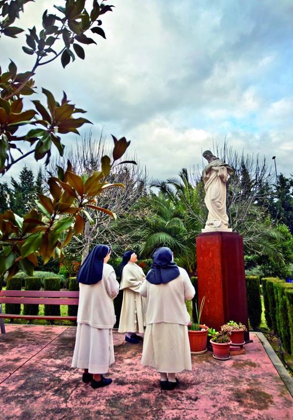 Abajo, tres concepcionistas  franciscanas pasean por  las inmediaciones del  monasterio de Madre de Dios. A la derecha, las tres monjas, junto a una figura de la Virgen.  :: justo rodríguez