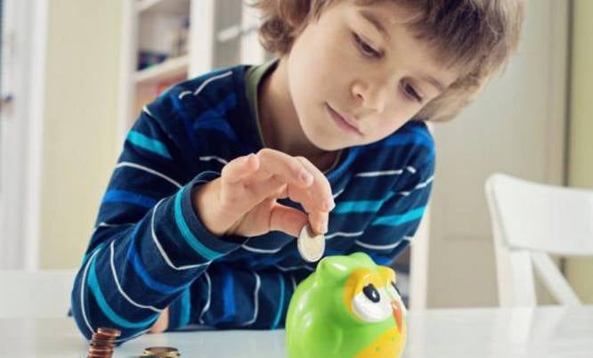 Un niño ahorra una moneda en una hucha. 