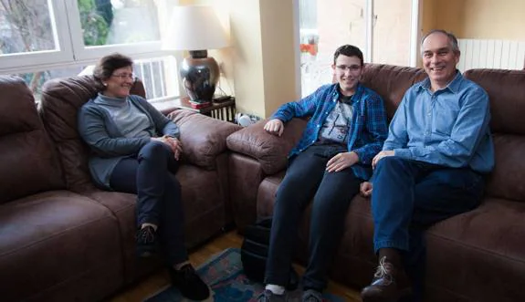 Juan, sentado en el salón de su casa de Logroño con sus padres, Francisco y Estrella, cuatro años después de que le diagnosticasen un osteosarcoma en el fémur. 