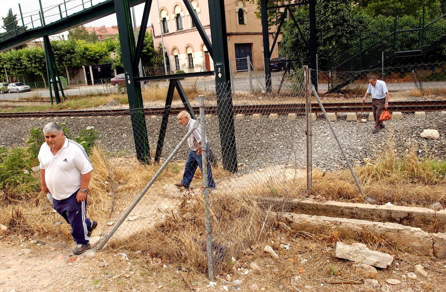 Peatones cruzando las vías a la altura de la Cerámica a través de un vallado roto.