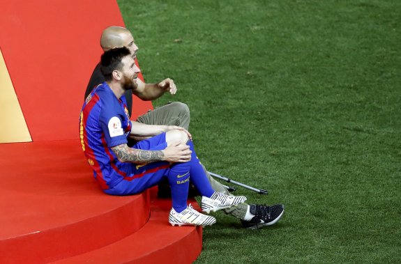 Messi y el lesionado Mascherano, sobre el césped del Vicente Calderón tras la conquista de la Copa. :: JuanJo Martín / efe