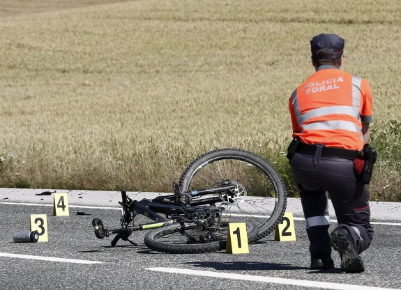 Un policía inspecciona el lugar donde murió atropellado un ciclista en Erice de Iza (Navarra). 