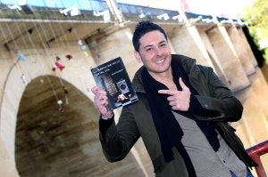 El logroñés Israel Esteban posa frente al puente de Piedra, donde ha colgado varios muñecos y peluches para promocionar su libro. ::                         JUAN                         MARÍN