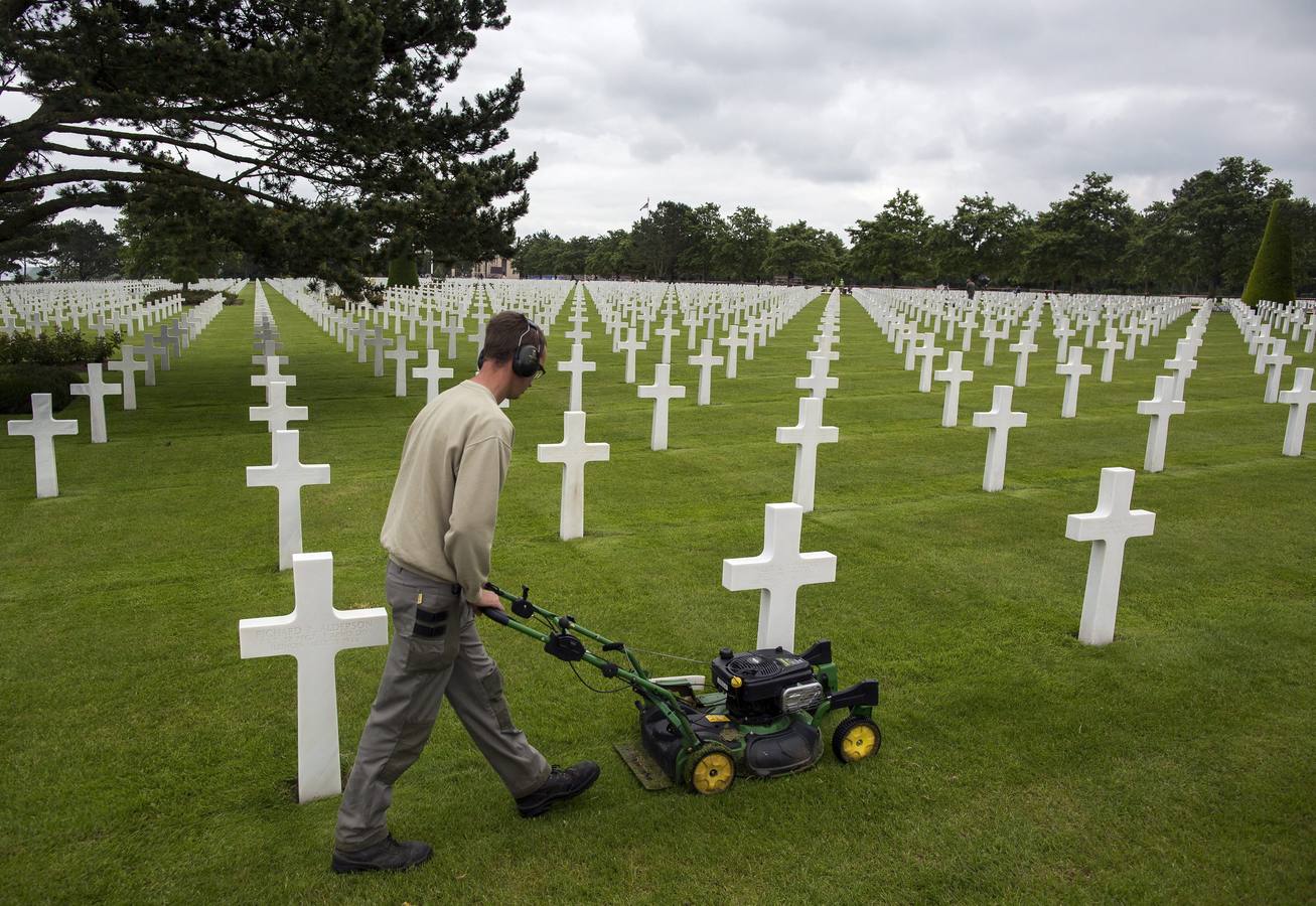 Un empleado corta el césped entre las tumbas del cementerio estadounidense cerca de Colleville-Sur-Mer.