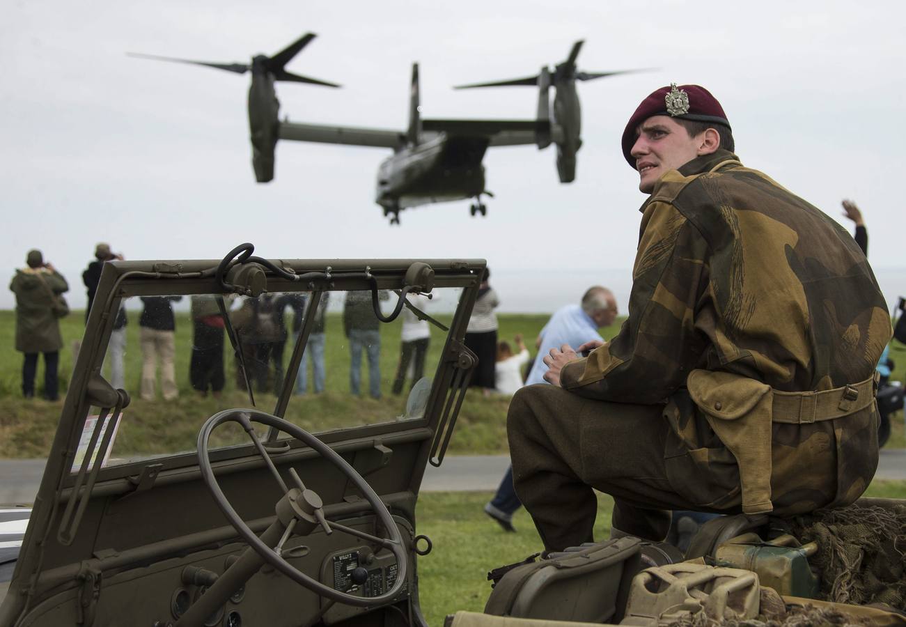 Un entusiasta de la historia de la Segunda Guerra Mundial, vestido con una réplica de un uniforme militar de la época, observa despegar a un Boeing-Bell V-22 de las Fuerzas Aéreas estadounidenses cerca del cementerio estadounidense próximo a Colleville-Sur-Mer.