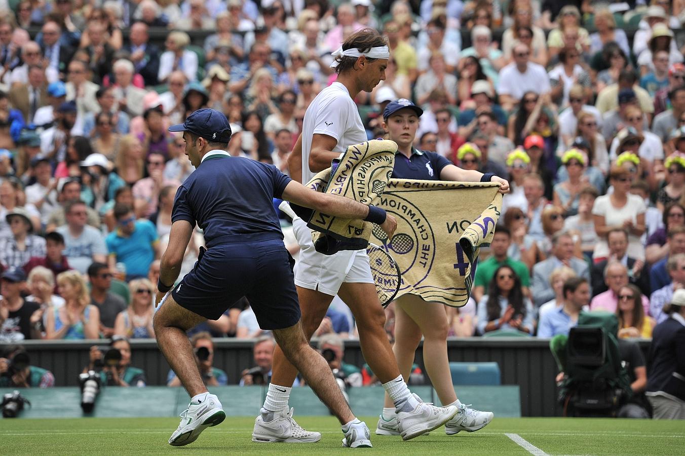 Nadal deja sus toallas a los recogepelotas antes de comenzar un punto.