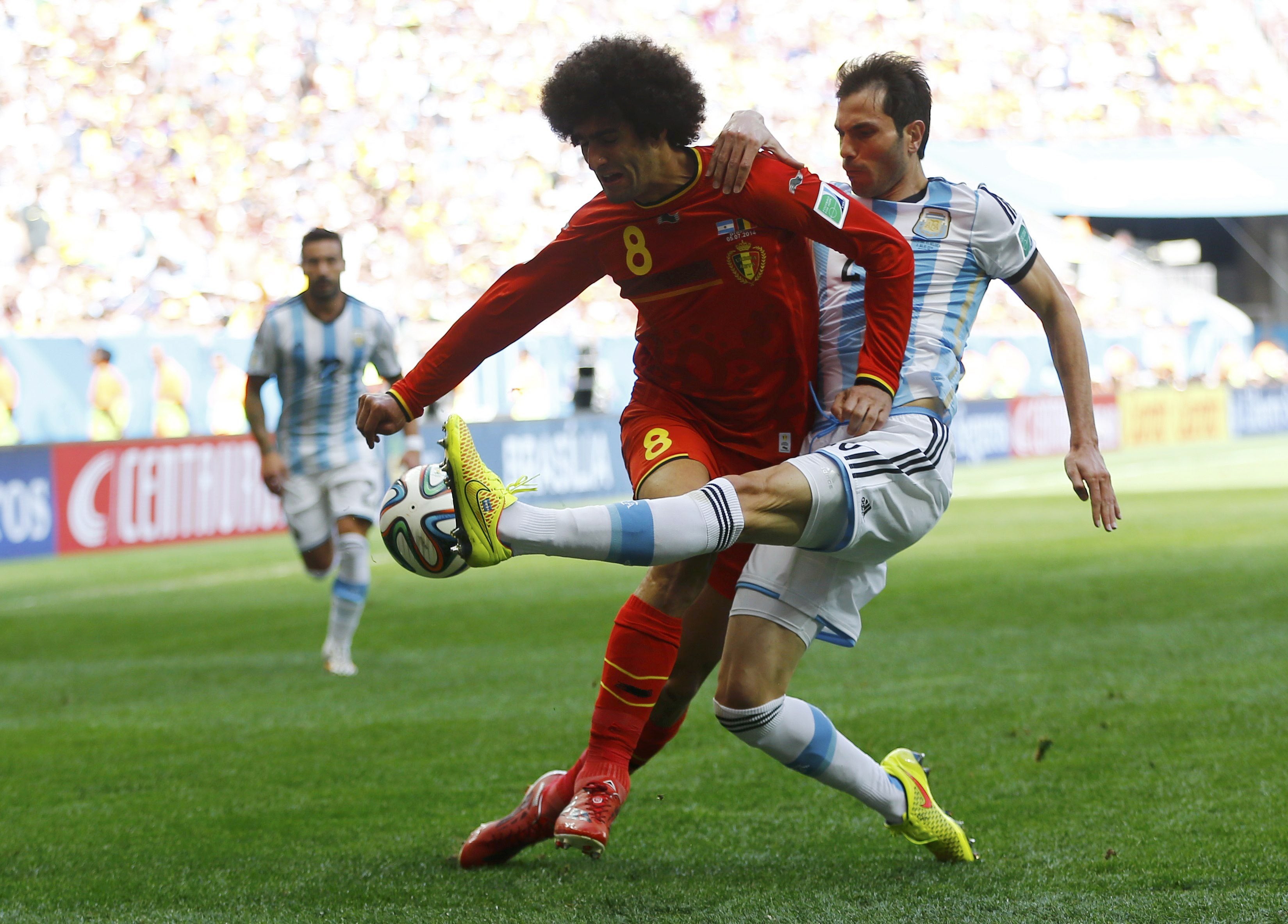 Fellaini protege el balón ante la presión de un futbolista argentino.